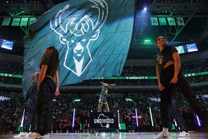 Milwaukee Bucks mascot Bango waves a flag with the Milwaukee Bucks logo